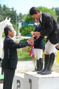 チルドレンライダーとジュニアライダーのS&H表彰式では日馬連副会長でもあるJOC竹田会長が優勝選手にカップとリボンを授与。写真はジュニアライダー林義昌選手